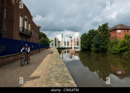 Ciclista a cavallo lungo il fiume percorso nel derby con il Mulino di seta Industrial Museum e il Jurys Inn in background Foto Stock