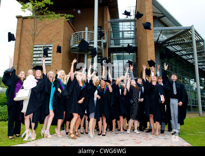 La collina di bordo gli Studenti Universitari sulla graduazione in posa per le fotografie sulla graduazione gettando le loro schede di mortaio cappelli in aria Foto Stock