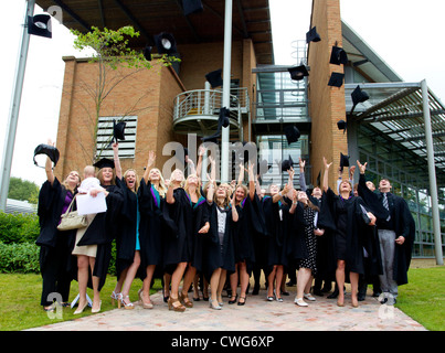 La collina di bordo gli Studenti Universitari sulla graduazione in posa per le fotografie sulla graduazione gettando le loro schede di mortaio cappelli in aria Foto Stock