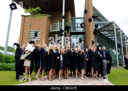 La collina di bordo gli Studenti Universitari sulla graduazione in posa per le fotografie sulla graduazione gettando le loro schede di mortaio cappelli in aria Foto Stock