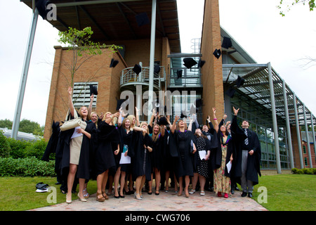 La collina di bordo gli Studenti Universitari sulla graduazione in posa per le fotografie sulla graduazione gettando le loro schede di mortaio cappelli in aria Foto Stock