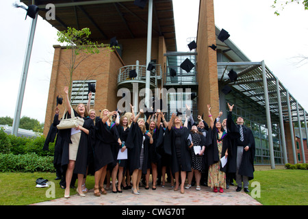 La collina di bordo gli Studenti Universitari sulla graduazione in posa per le fotografie sulla graduazione gettando le loro schede di mortaio cappelli in aria Foto Stock