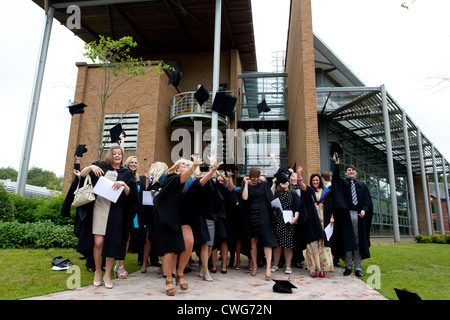 La collina di bordo gli Studenti Universitari sulla graduazione in posa per le fotografie sulla graduazione gettando le loro schede di mortaio cappelli in aria Foto Stock