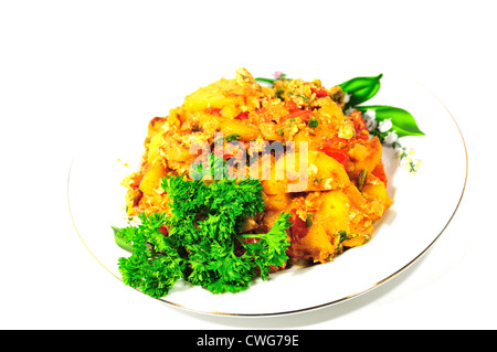 Piastra con patate fritte con pomodori e uova, decorate con prezzemolo su uno sfondo bianco. Foto Stock