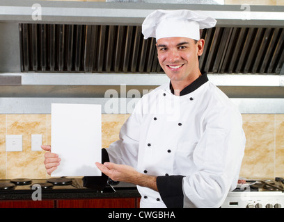 Giovane maschio chef azienda scheda bianca in cucina Foto Stock