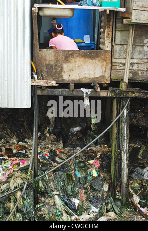 La Malesia, Borneo, Semporna, donna lavaggio nella palafitta di spazzatura sotto Foto Stock