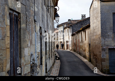 Due persone che camminano giù per una strada stretta a Saint Emilion, Francia meridionale Foto Stock