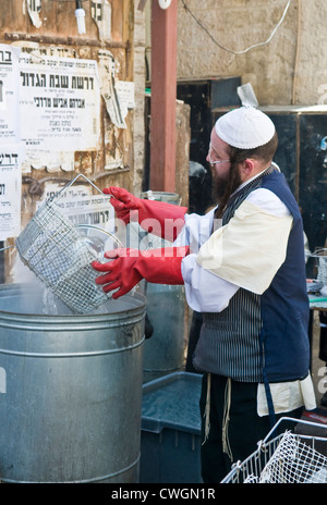 Un ultra ortodosso l uomo si sta preparando per la festa ebraica della Pasqua mediante la purificazione dei piatti a Gerusalemme in Israele Foto Stock