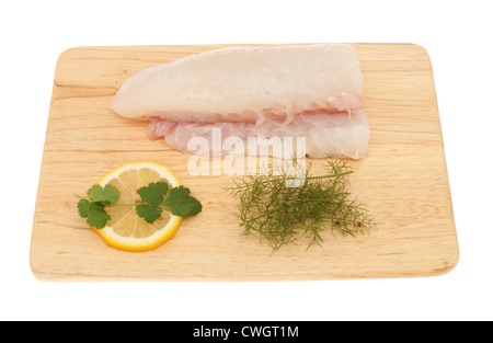 Crudo fresco filetto di merluzzo su una scheda con il limone, prezzemolo e finocchio isolata contro bianco Foto Stock