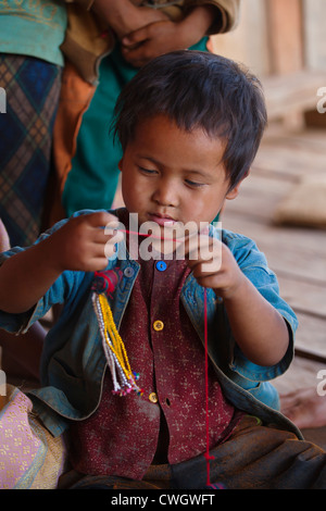 Un bambino da ANN tribù gioca con cordone a lavorare in un villaggio nei pressi di Kengtung o KYAINGTONG - Myanmar Foto Stock