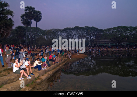 Vista orizzontale di turisti che si siedono insieme intorno ad un lago di guardare il tramonto su Prasat Angkor Wat. Foto Stock