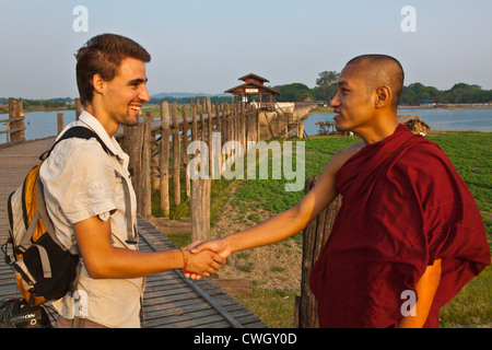 Un monaco birmano e un turista francese riunisce in teak U BEINS ponte che attraversa il lago Taungthaman AMARAPURA, MYANMAR Foto Stock