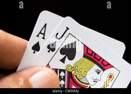 Le carte blackjack tenuto a mano su sfondo nero Foto Stock