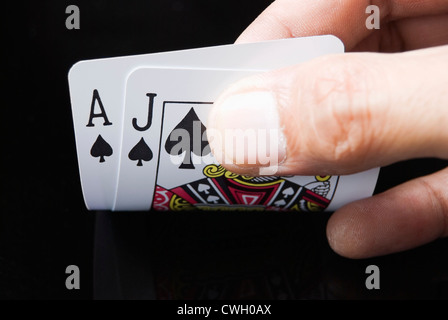 Le carte blackjack tenuto a mano su sfondo nero Foto Stock