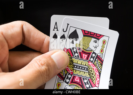 Le carte blackjack tenuto a mano su sfondo nero Foto Stock