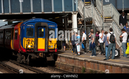 I passeggeri in attesa come una classe 455 treno nella zona sud ovest di treni approcci livrea Clapham Junction station, Inghilterra. Foto Stock