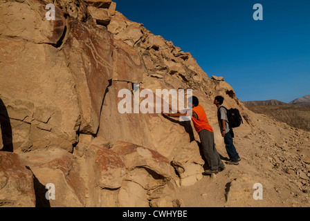 Guide peruviana sottolineando incisioni rupestri a Palpa Perù di petroglifi Chichictara America del Sud Foto Stock