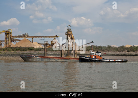 Di rimorchiatori e di chiatte sul Fiume Tamigi vicino a Tilbury Dock nel Kent essendo caricato con ghiaia per impiego nel settore della costruzione Foto Stock