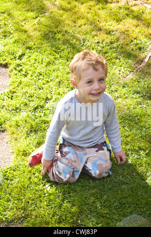 Tre anni di vecchio ragazzo giocando su un prato, Cornwall, Inghilterra, Regno Unito. Foto Stock