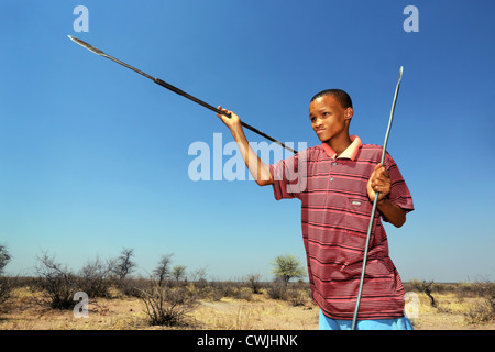 Ragazzo del San indigene tribù getta una lancia, Namibia, deserto Kalahari Foto Stock