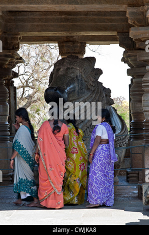 Le donne indiane adorare il Nandi Bull monolite. Tempio Hoysaleswara. Halebidu. India Foto Stock