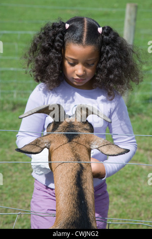 Ragazza giovane alimentando ad una capra in occasione di una visita ad una fattoria di città, Foto Stock