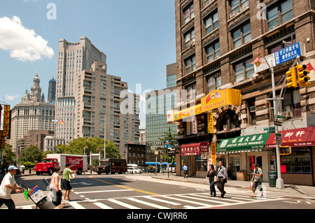 Le auto parcheggiate costeggiano East Broadway passando davanti a una fila di edifici storici con fuochi d'incendio e aziende locali nella Chinatown di Manhattan, New York City Foto Stock