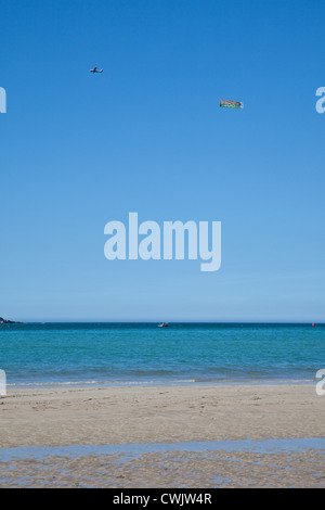 Spia traino aeromobili banner pubblicitario Daymer Bay beach nei pressi di roccia e Padstow, Cornwall, Inghilterra, Regno Unito. Foto Stock