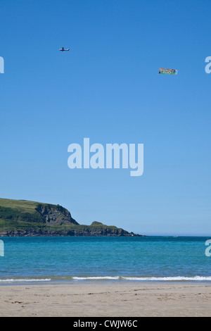 Spia traino aeromobili banner pubblicitario Daymer Bay beach nei pressi di roccia e Padstow, Cornwall, Inghilterra, Regno Unito. Foto Stock