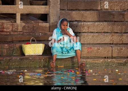 Il vecchio donna indiana per la pulizia dei denti di lei con il dito in presenza di sporco di acque inquinate del fiume Gange a Varanasi, Uttar Pradesh, India Foto Stock