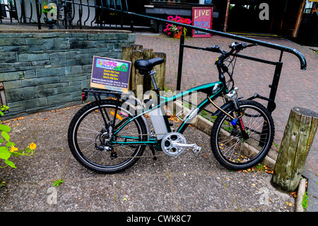 Un elettricamente assistita bicicletta verde pubblicizzato per la vendita o il noleggio lungo la banchina in Bowness-on-Windermere, Cumbria, Regno Unito Foto Stock
