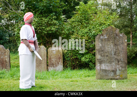 Lo Spaventapasseri a kettlewell festival raffigurante un uomo nel sagrato della chiesa con la piastra di raccolta Foto Stock