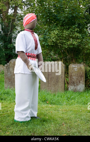 Lo Spaventapasseri a kettlewell festival raffigurante un uomo con piastra di raccolta nel sagrato della chiesa Foto Stock