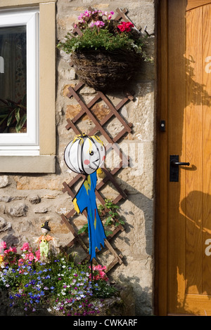 Wind toy spaventapasseri a kettlewell festival in piedi in vaso di fiori colorati Foto Stock