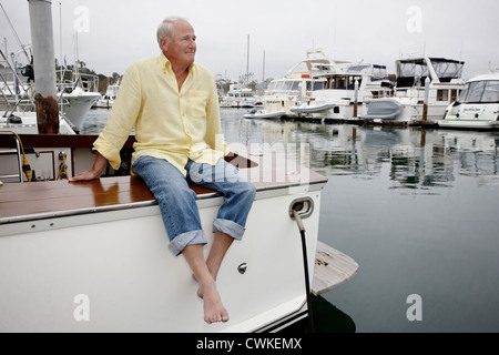 Uomo sorridente seduto sulla barca in marina Foto Stock