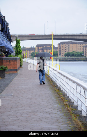 Giovane uomo a camminare in città su un wet 'Summer' giorno in Glasgow Foto Stock