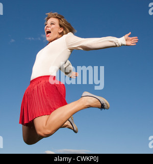 Fortunatamente jumping donna su un luminoso cielo blu Foto Stock