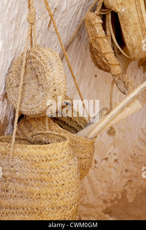 Cestini di paglia e strumenti in legno appeso ad un muro di pietra Foto Stock