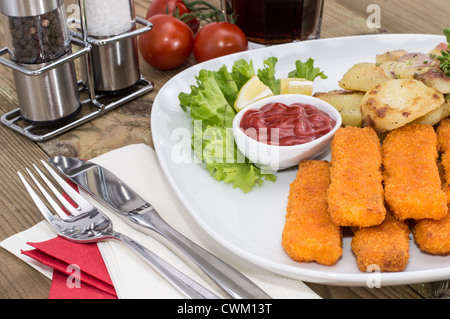 I Bastoncini di pesce con patate fritte su sfondo di legno Foto Stock