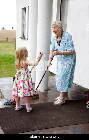 Il polacco grande nonna e pronipote spazzatrici e portico con straccio entrata età 86 e 4. Zawady Polonia centrale Foto Stock