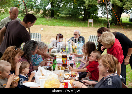 Extended quattro generazioni della famiglia polacca avente una cena all'aperto nel loro cortile. Zawady Polonia centrale Foto Stock