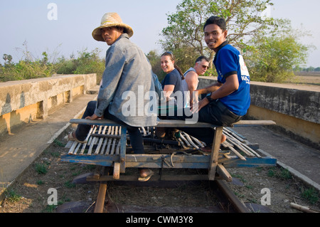 Vista orizzontale di cambogiani e i turisti occidentali a cavallo sul famoso Treno di bambù o di Nori, a Battambang. Foto Stock