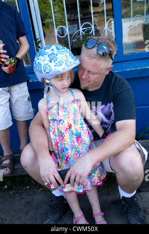 Papà consolante figlia indossando il casco e un abito dopo un lungo viaggio in bicicletta i 4 anni di età e 37. Mala Wola Polonia centrale Foto Stock