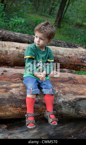 Ragazzo polacco age 2 prendendo una pausa di bicicletta su registri su un sentiero di registrazione attraverso la foresta nazionale. Zawady Polonia centrale Foto Stock