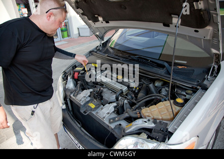 Uomo età 37 il controllo del livello dell'olio sotto il cofano della sua auto presso la stazione di gas con un bastone dip. Rzeczyca Polonia centrale Foto Stock