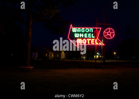 La ruota del carro Motel insegna al neon illuminata di notte sul percorso 66 Foto Stock