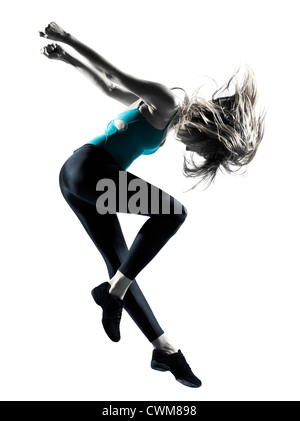 Vista laterale del biondo donna dai capelli facendo ginnastica salto in studio su sfondo bianco Foto Stock