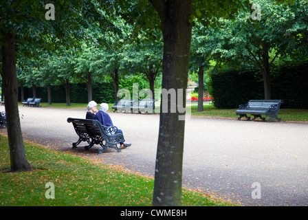 Due anziane signore seduto sul banco di lavoro su vasta passeggiata in Regents Park a Londra REGNO UNITO Foto Stock
