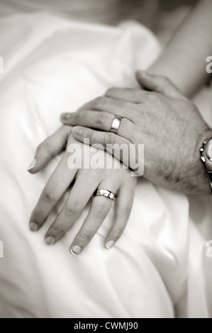 Toccando le mani di una sposa e lo sposo che mostra i loro anelli di nozze il giorno delle nozze in bianco e nero o in bianco e nero Foto Stock