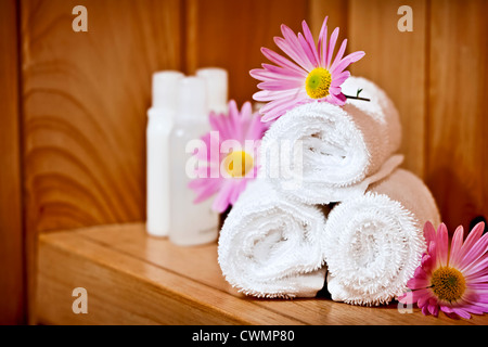 White arrotolato asciugamani spa con prodotti per la cura del corpo Foto Stock